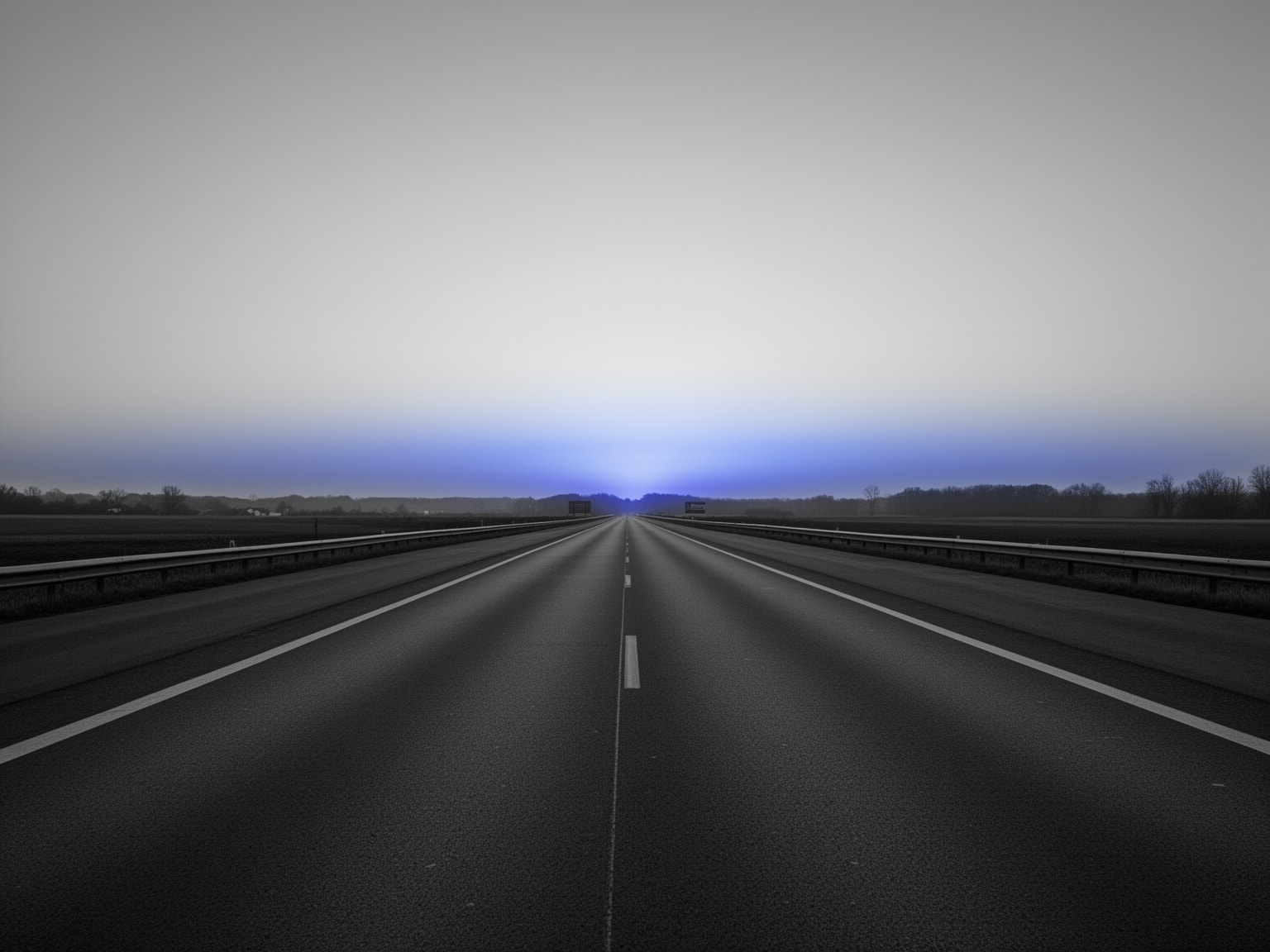 Empty highway with soft indigo glowing horizon under a dramatic black and white sky